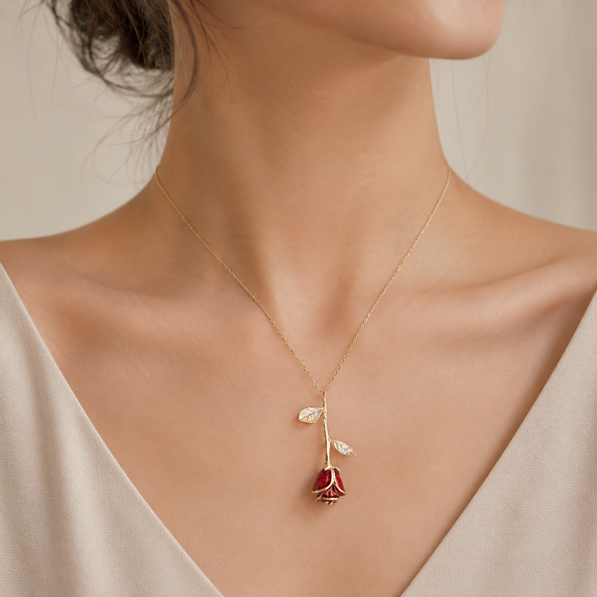 Gold-tone rose pendant necklace shown against a white background.