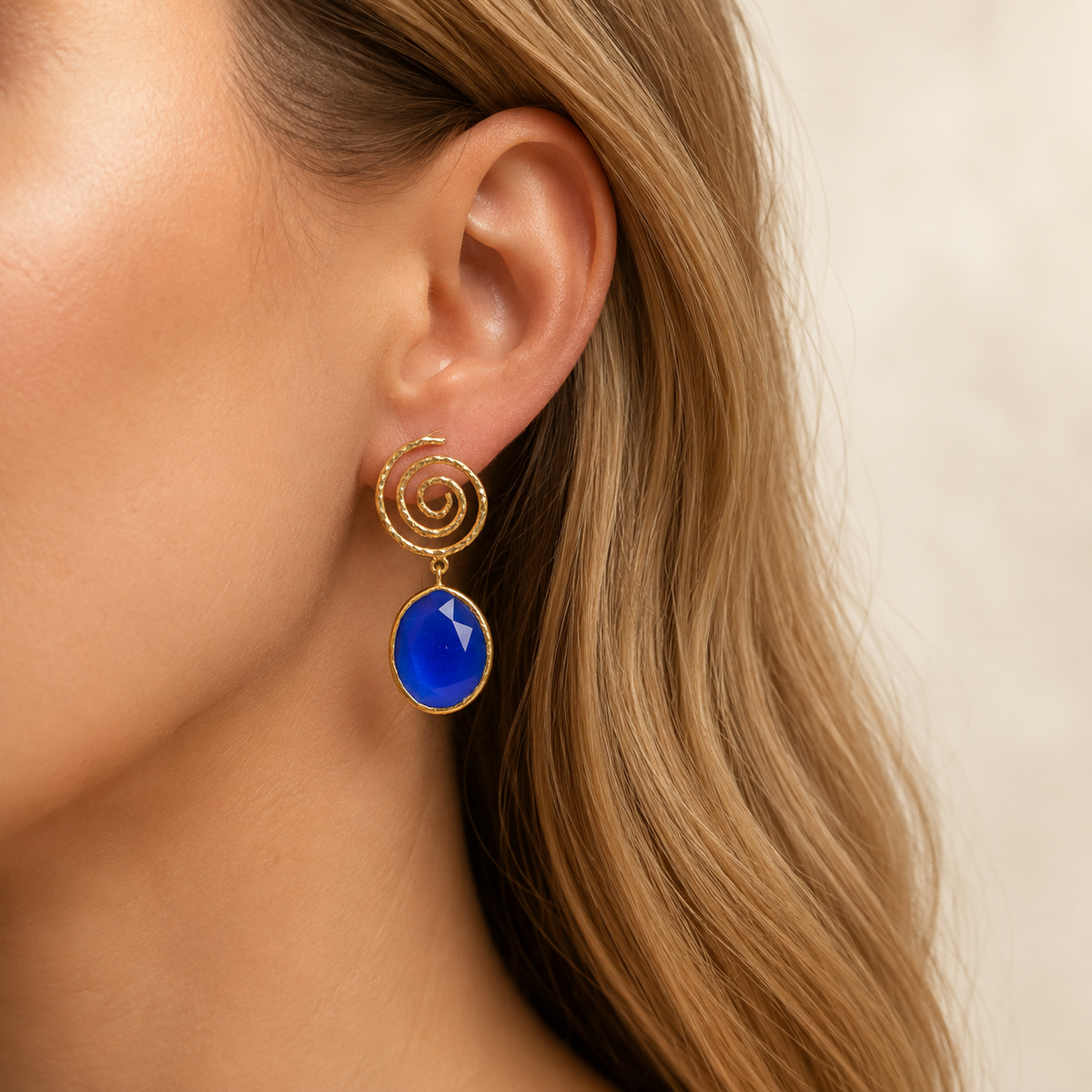 Pair of gold-tone spiral earrings with navy blue faceted drops.
