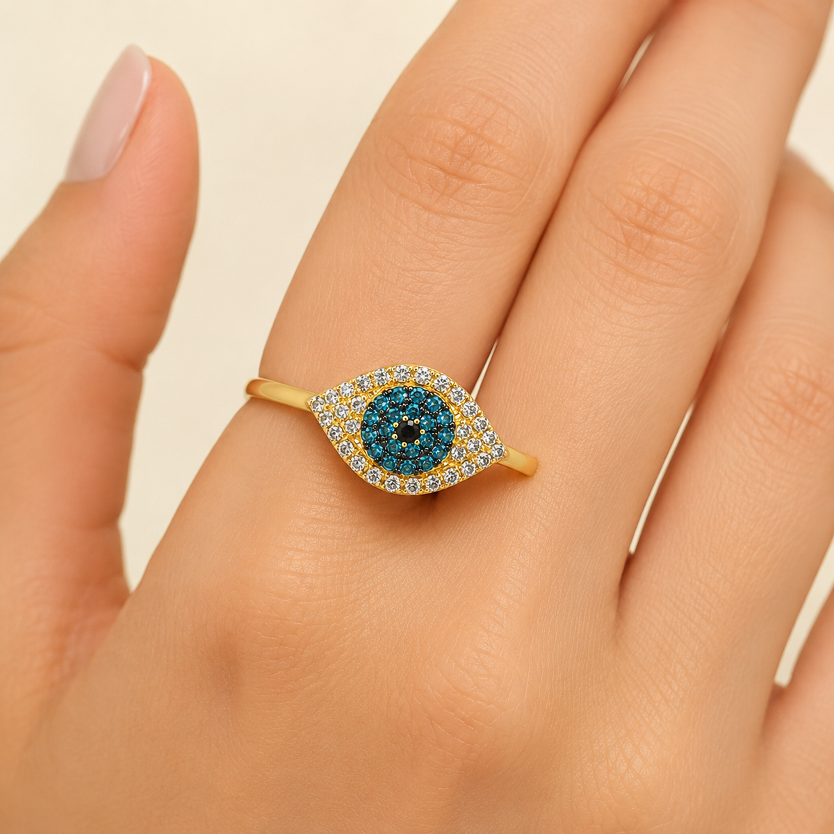 Gold-tone evil eye ring shown from the front with bright blue accents.