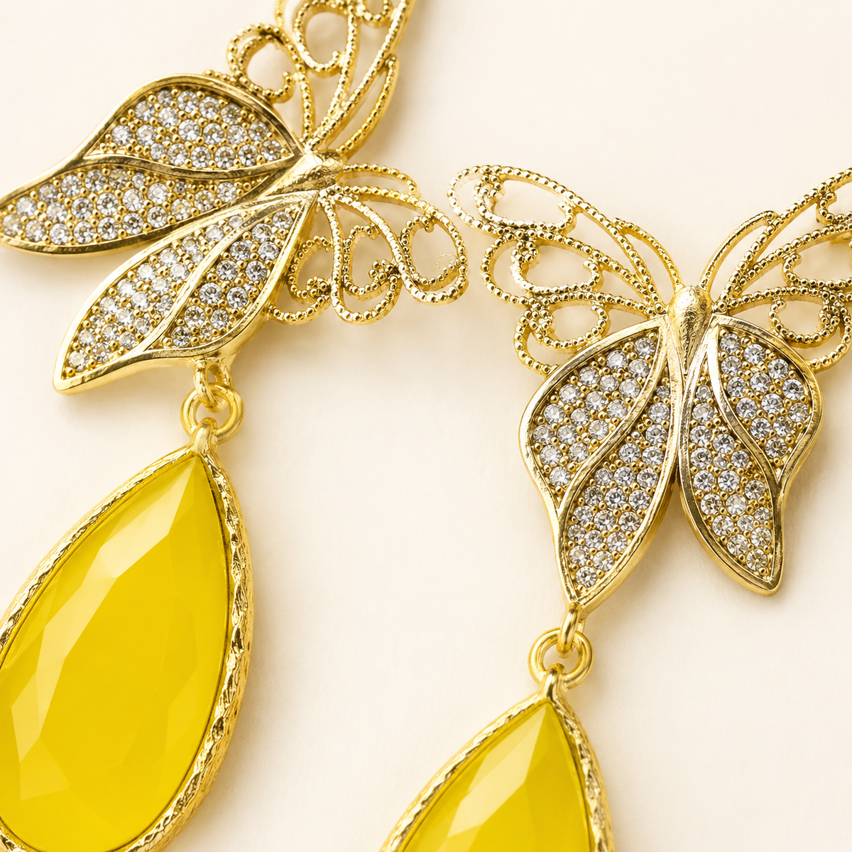 Close-up of butterfly drop earrings with CZ sparkle and gold-plated detailing.