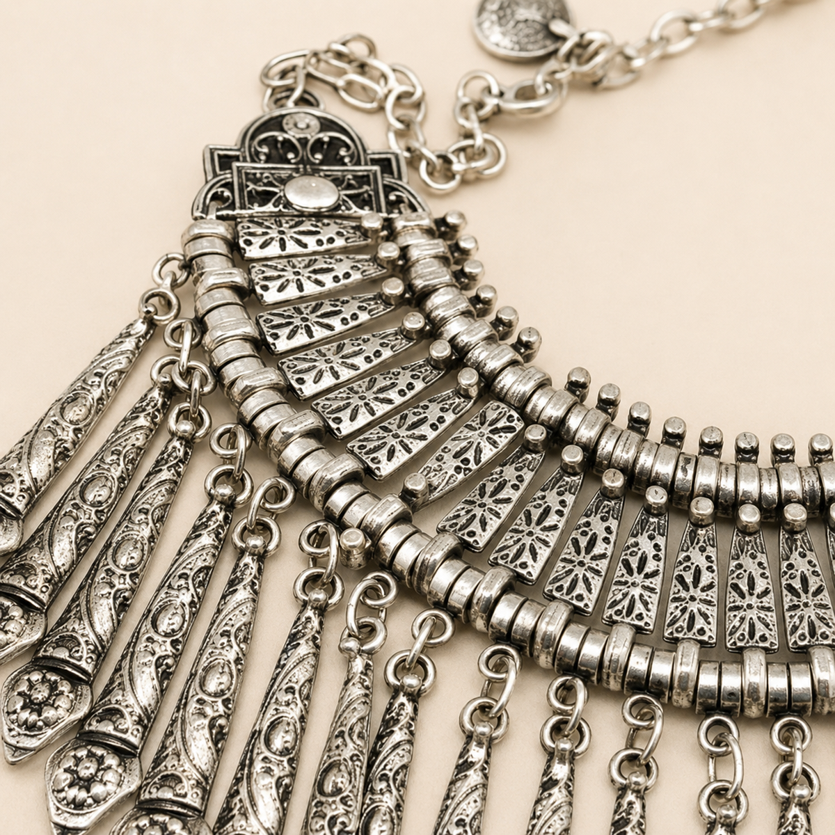 Close-up view of the silver-tone paddle fringe necklace with ornate textured accents.