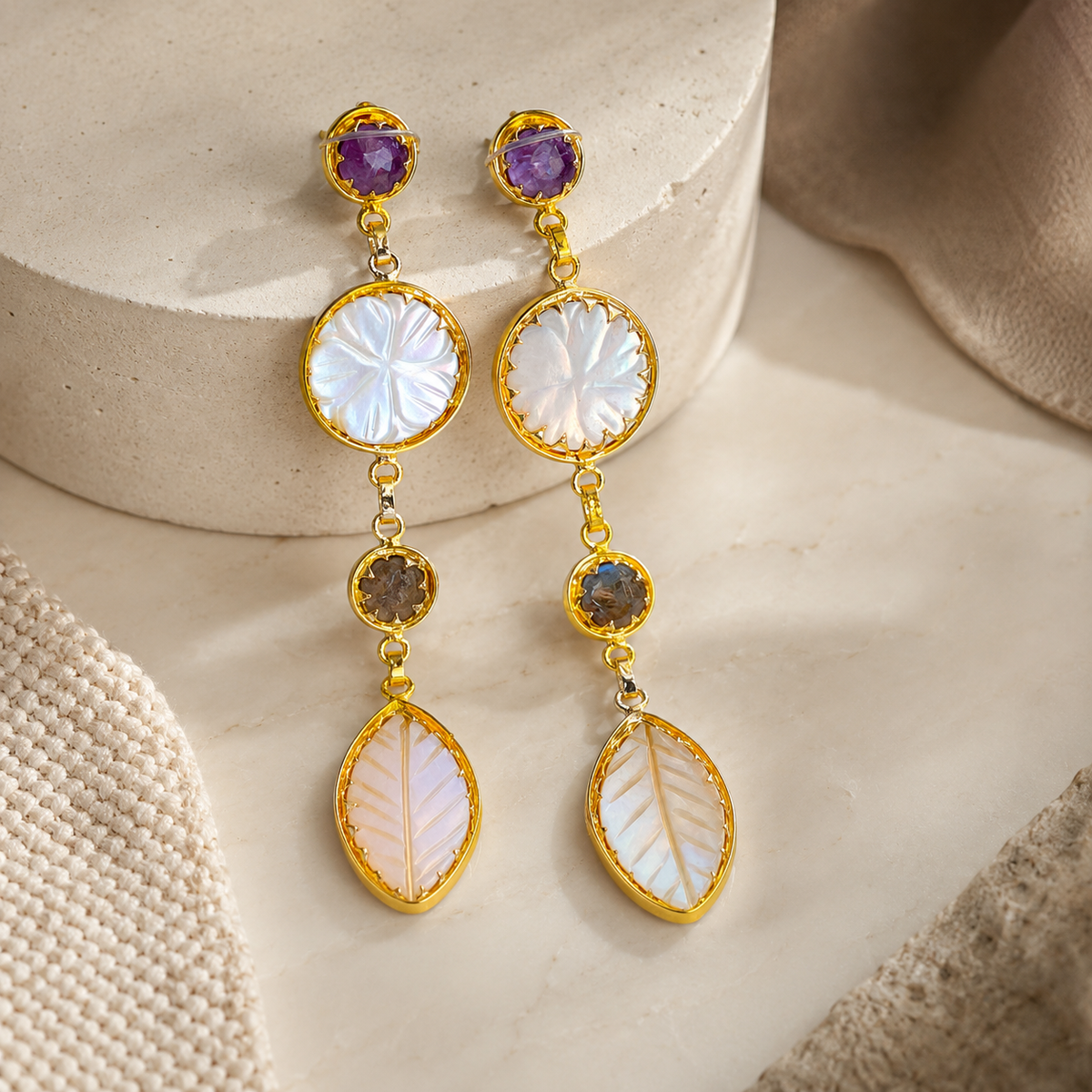 Angle view of gold-plated drop earrings with a layered multi-stone design.