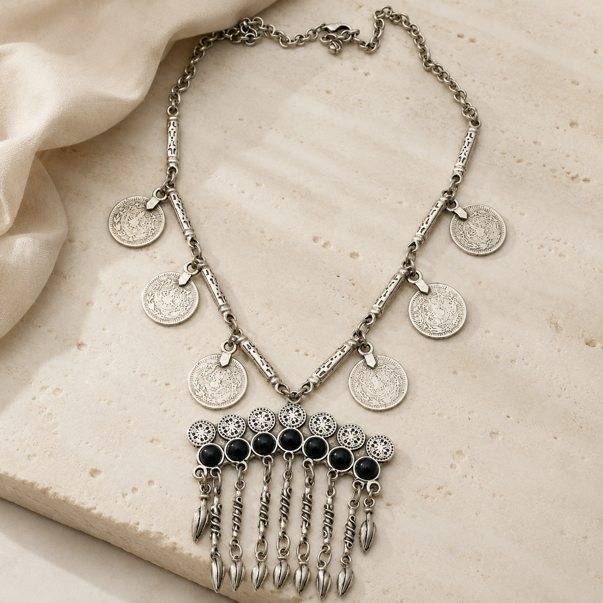 Silver-tone statement necklace with coin charms and a fringe bib silhouette.