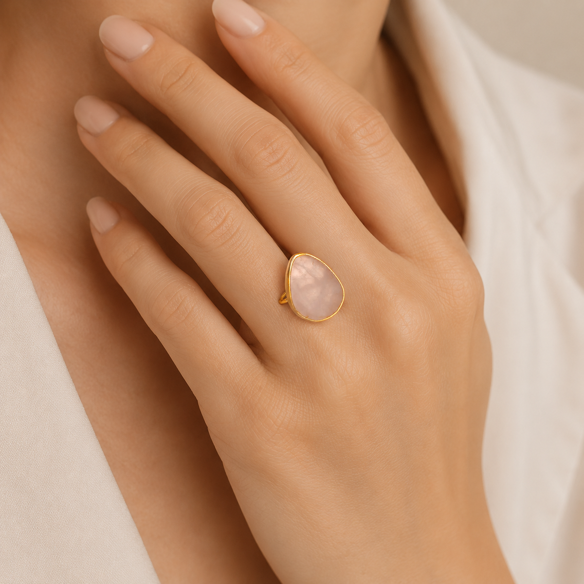 Close view of a rose quartz teardrop ring in a gold-plated setting.