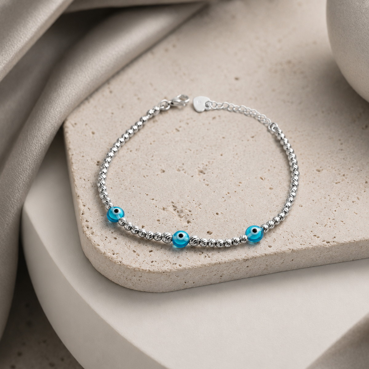 Angled view of a silver-tone beaded bracelet with blue eye accents.