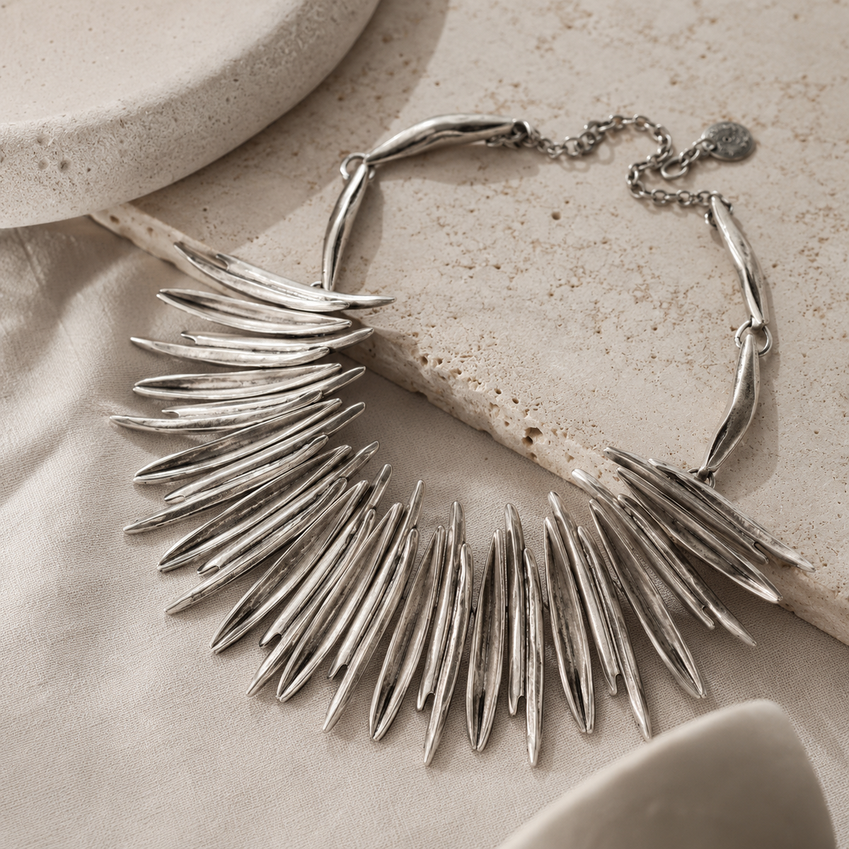 Angled view of a silver-tone spiky collar necklace with a sculptural finish.