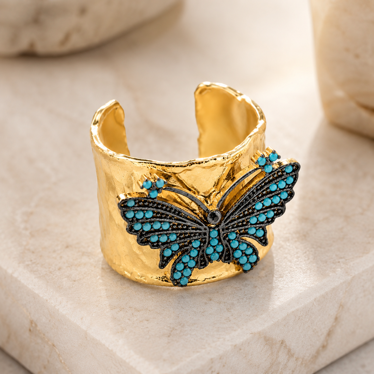Angled view of a gold-plated butterfly cuff ring with turquoise blue details.