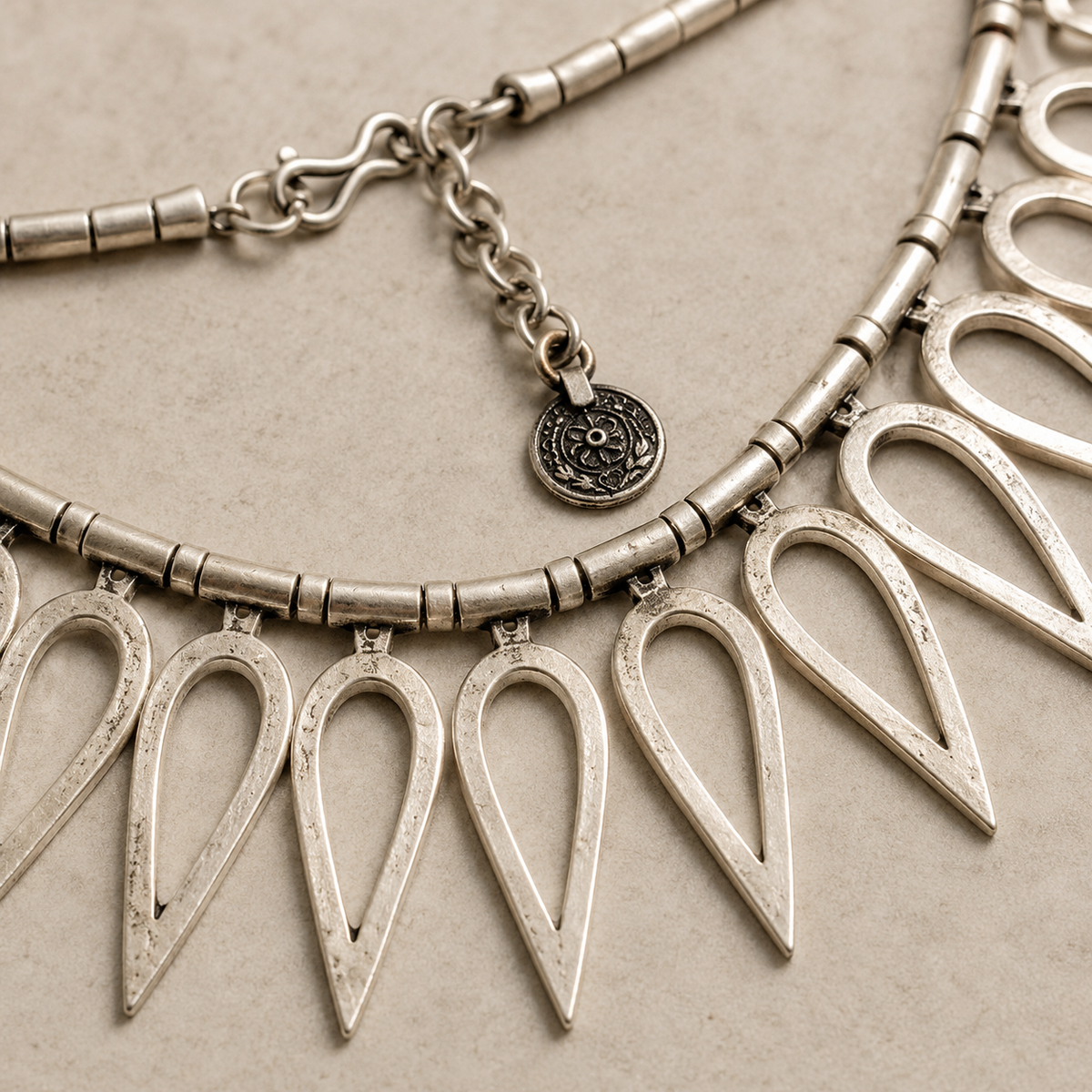 Close view of the silver-tone teardrop links and textured collar chain.