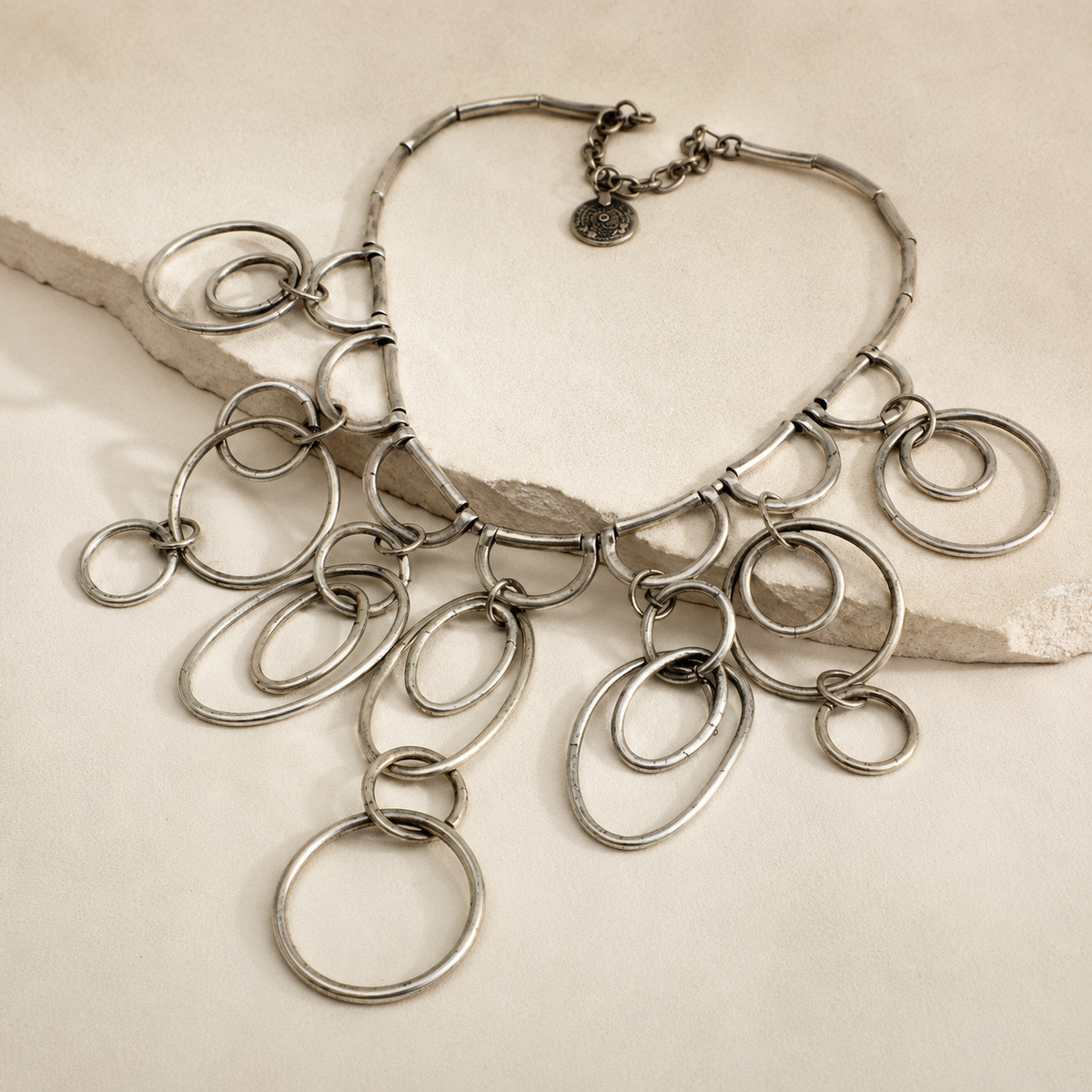 Angled view of the silver-tone ring drop necklace with layered circular links.