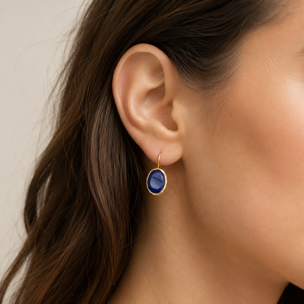 Gold-plated drop earrings with deep blue faceted oval stones shown front view.