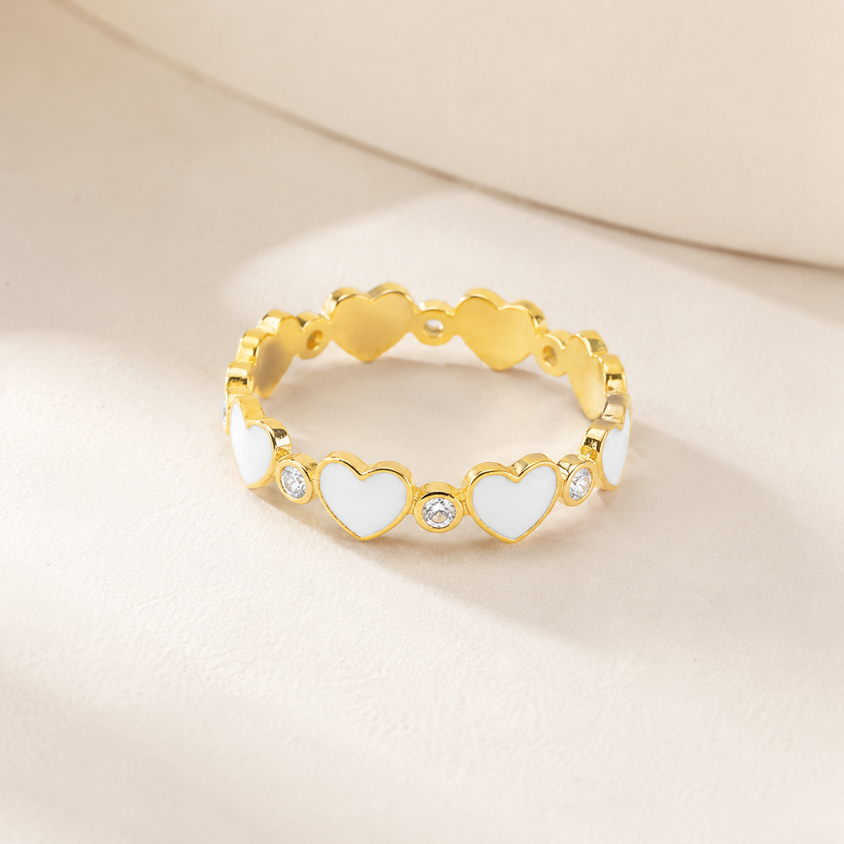 Angled view of a gold-plated heart ring with clear stone details.