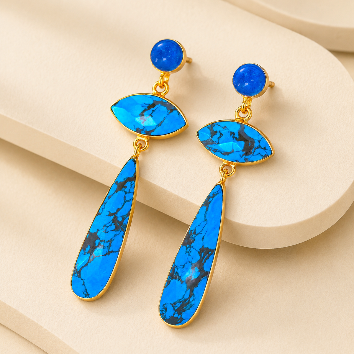 Angle view of long turquoise drop earrings with polished gold-plated trim.