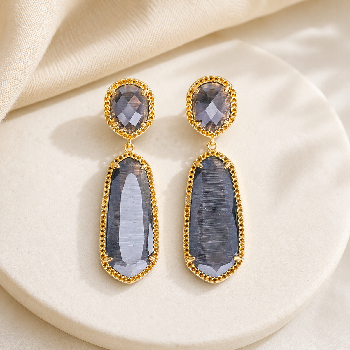 Gold-plated earrings with a long drop shape and smoky gray stones.