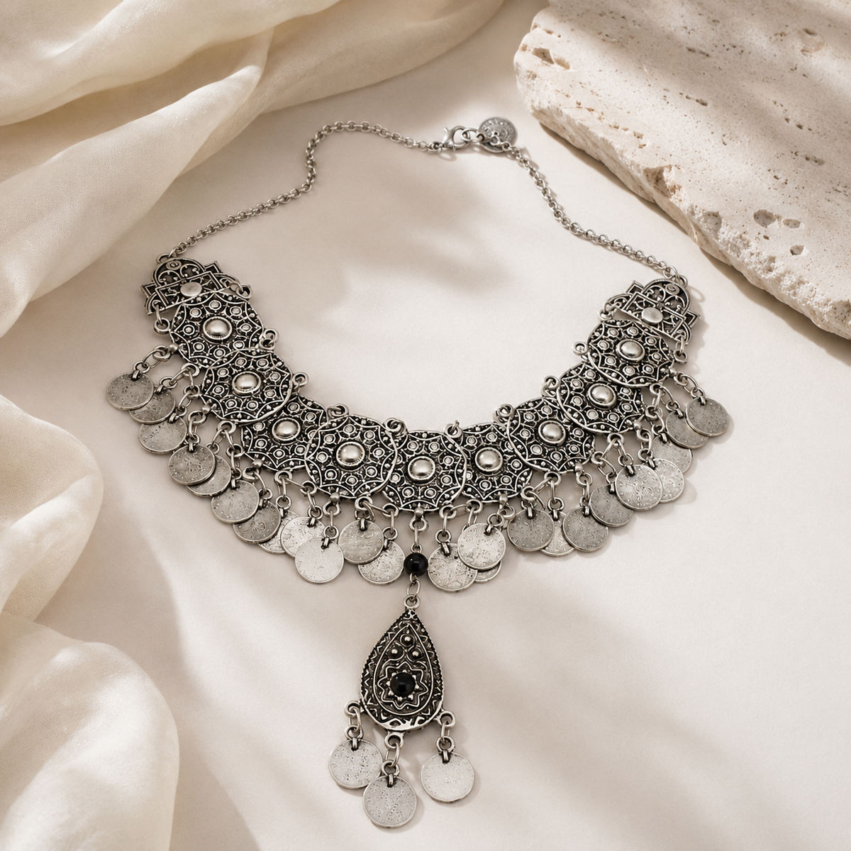 Silver-tone statement necklace with layered coin fringe and black stone detail.