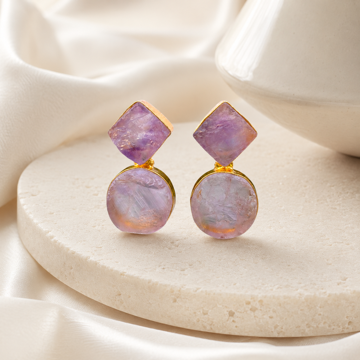 Gold-plated drop earrings with layered rough amethyst stones on a white background.
