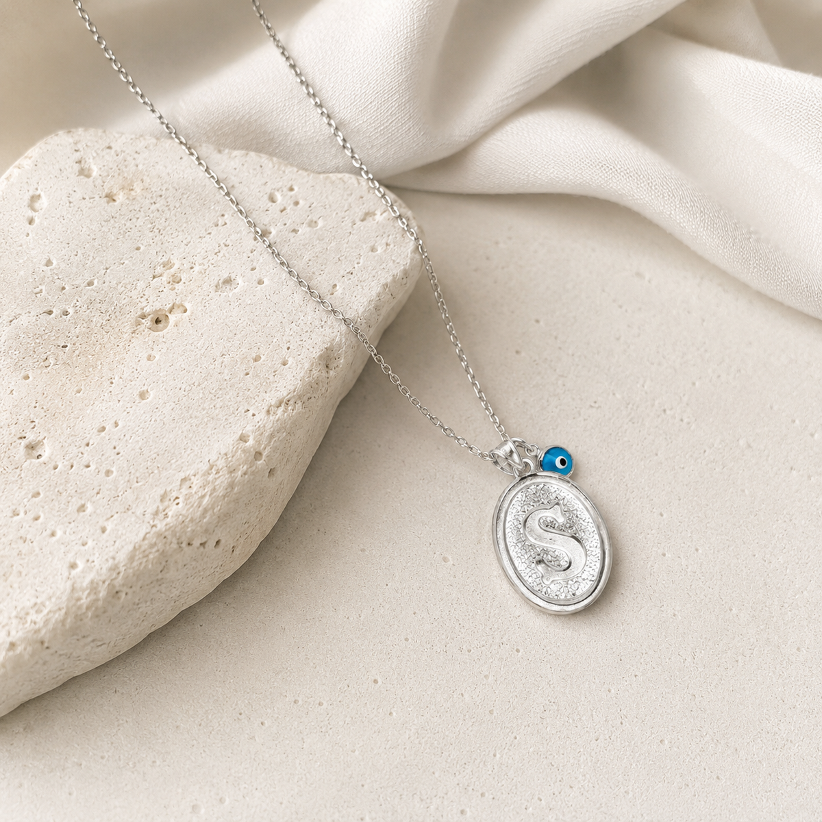 Personalized initial necklace styled on a neutral background with a soft silver-tone look.