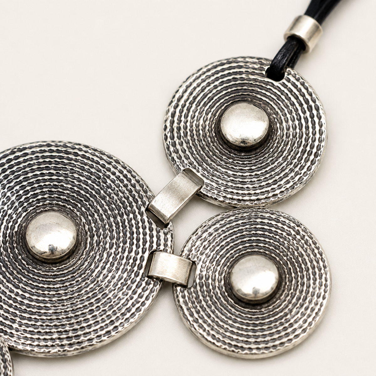 Close view of the necklace’s textured concentric disc details and silver-tone finish.