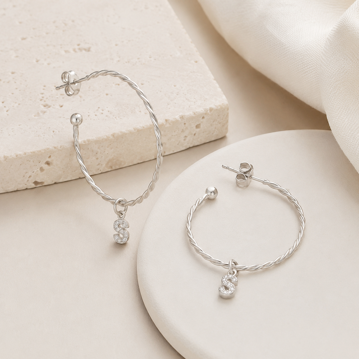 Angle view of personalized twisted hoop earrings with CZ initial charm.