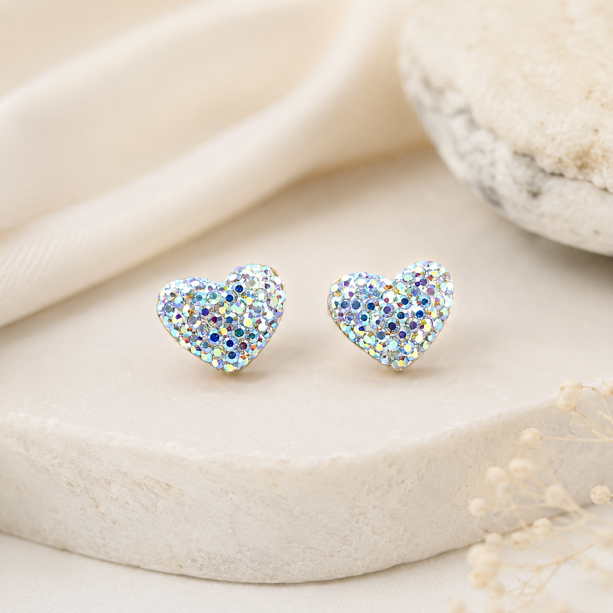 Heart-shaped stud earrings with a shimmering crystal-like surface on a white background.
