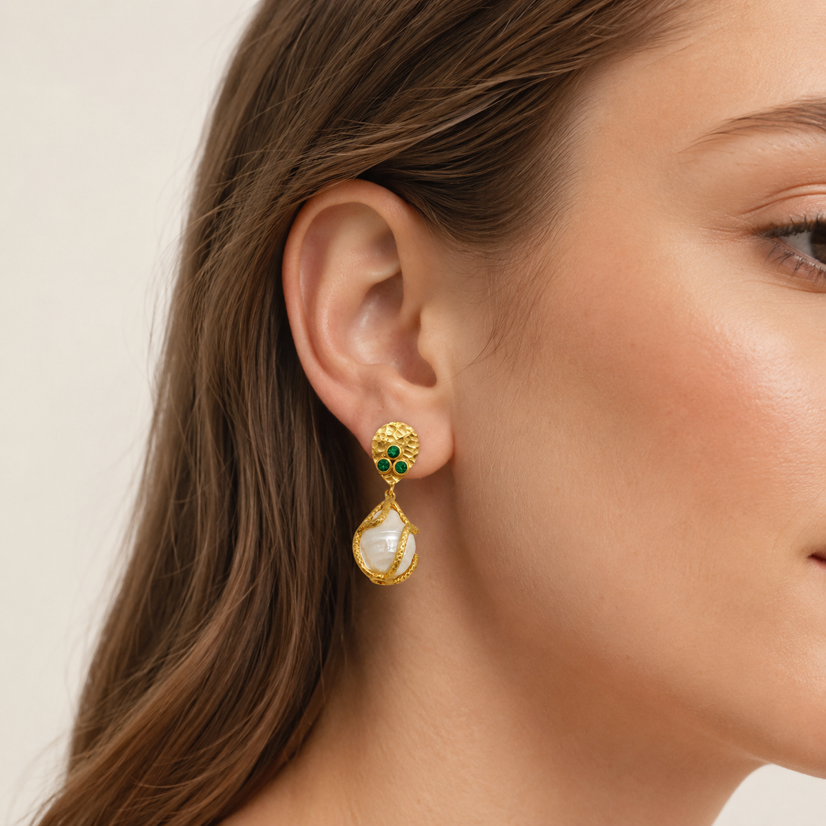 Gold-plated drop earrings with green CZ accents and a pearl-like center shown from the front.
