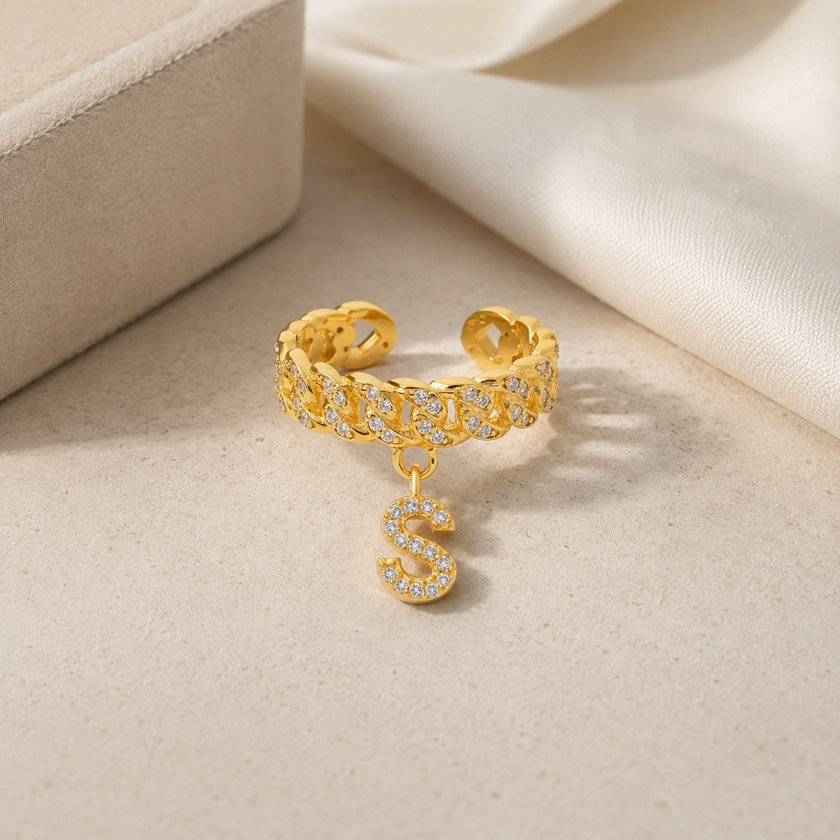 Gold-tone initial cuff ring with a textured band and clear stone details.