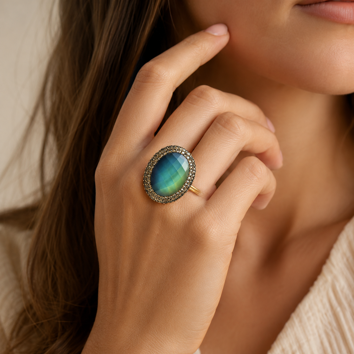 Round color-changing ring with a faceted blue-to-green center stone and a sparkling gold-tone halo.