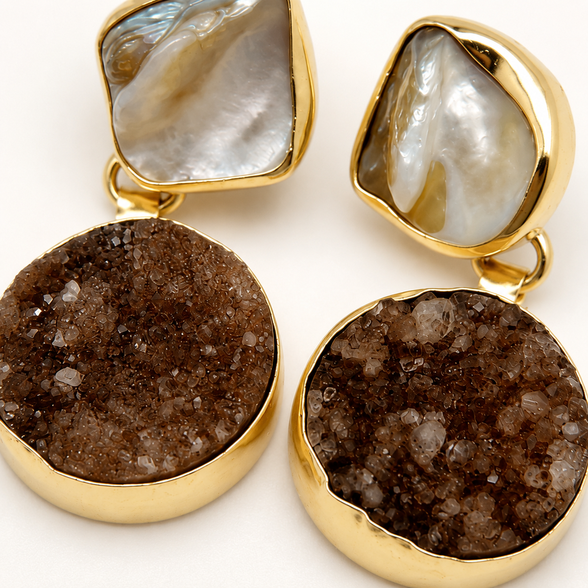 Close-up of gold-plated earrings with textured black cluster stones.