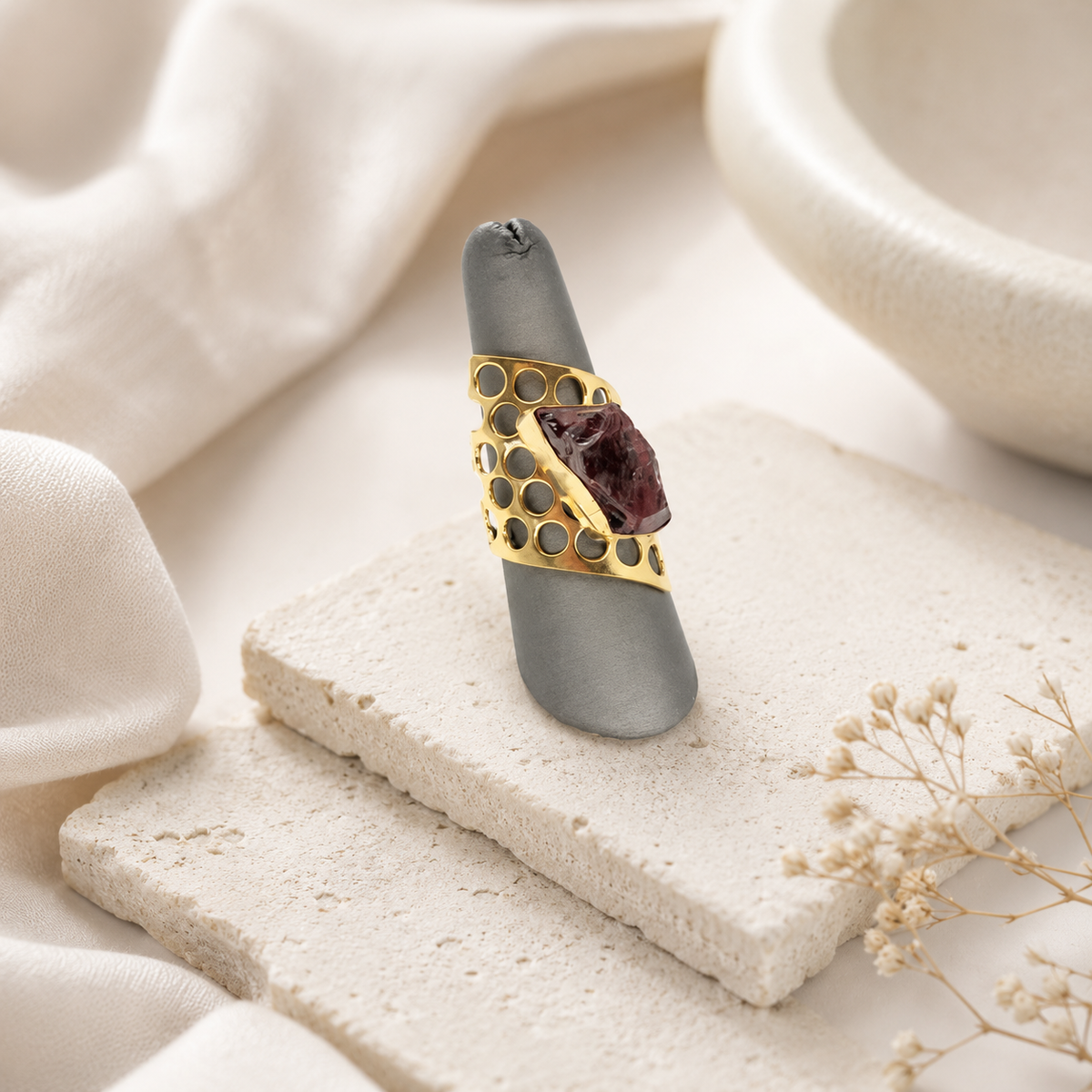 Gold-plated statement ring with a raw garnet center on a clean background.