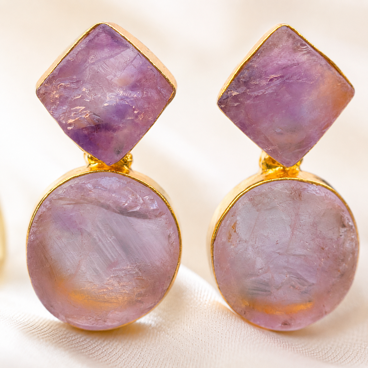 Close view of rough amethyst stones framed in gold-plated metal.