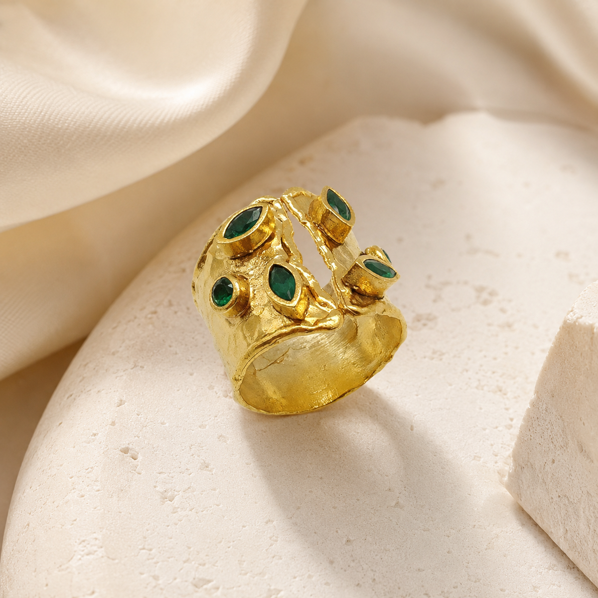 Gold open cuff ring with emerald green stones from an angle