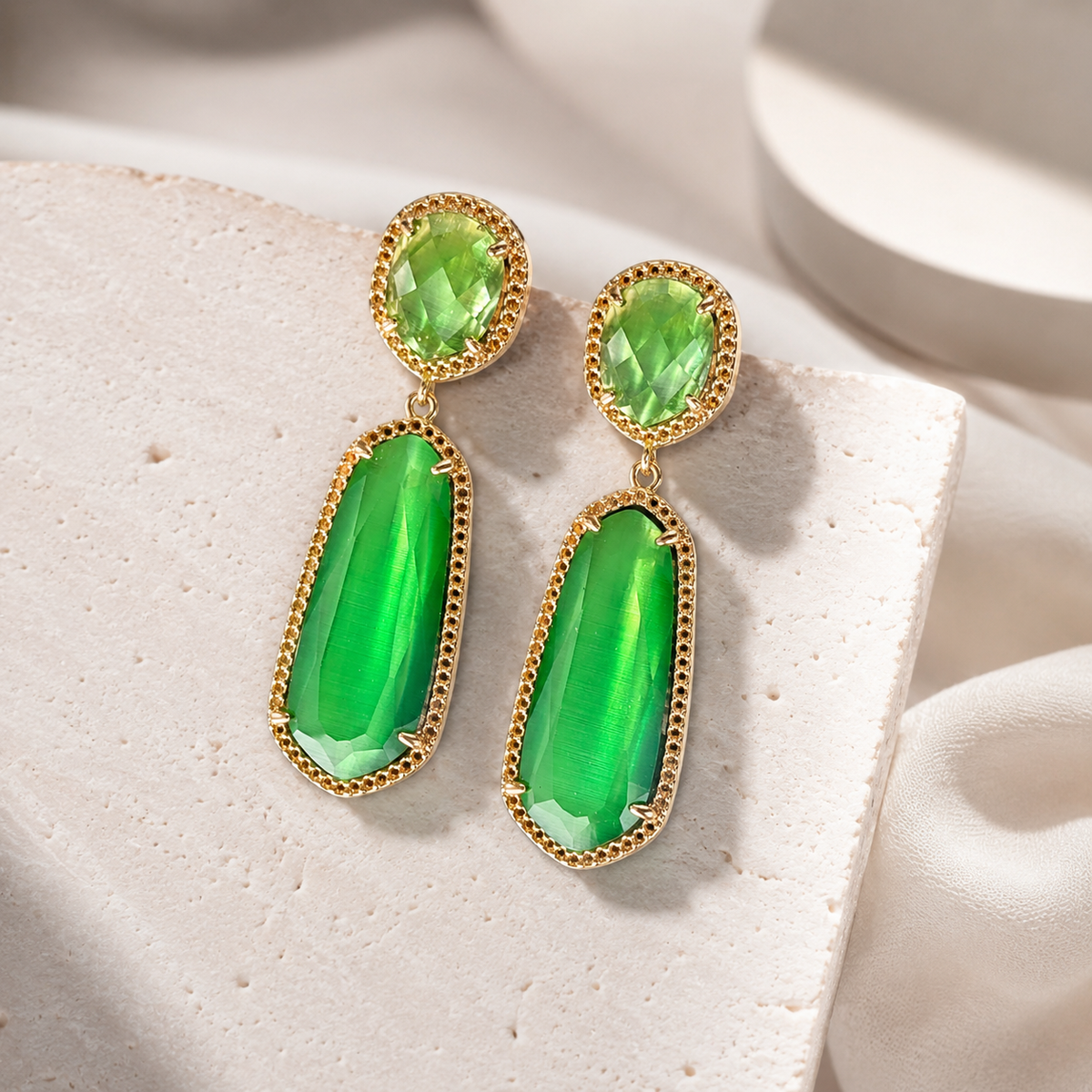 Front view of emerald green cat eye drop earrings in gold-plated metal.