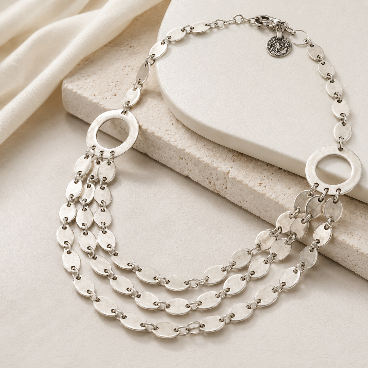 Angled view of the layered silver oval link necklace with multiple strands.