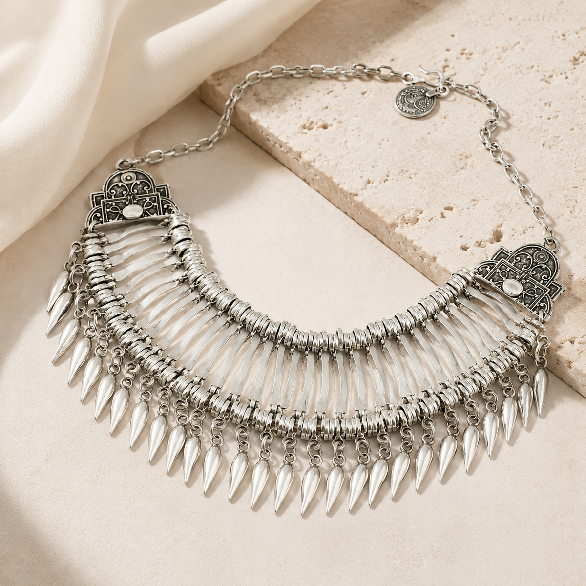 Silver-tone statement necklace with layered fan details and teardrop accents.