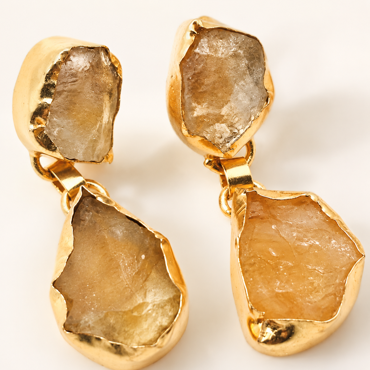 Close-up of rough citrine-like stones set in gold-plated earrings.