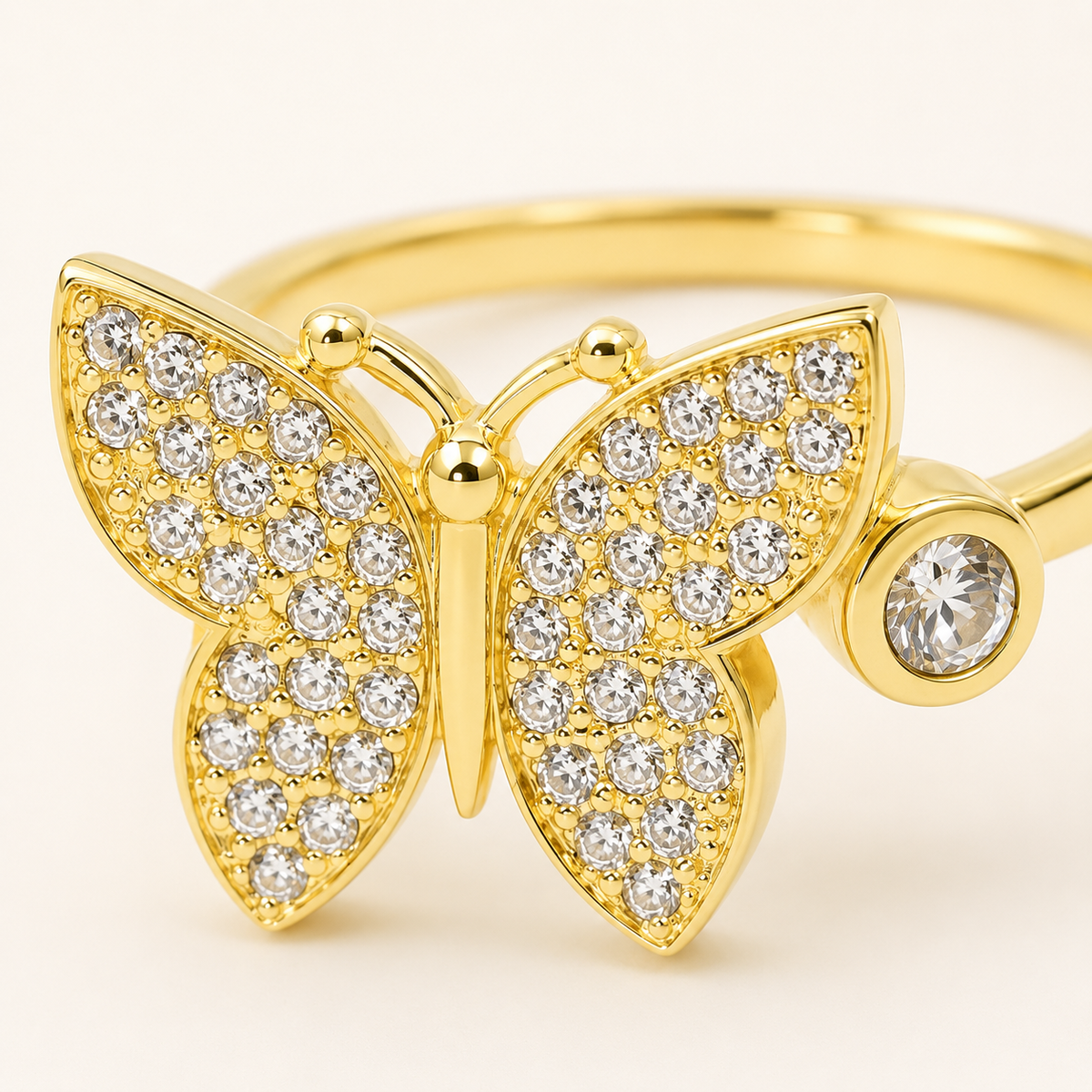 Close view of a butterfly ring with pavé-style CZ accents and a polished gold look.