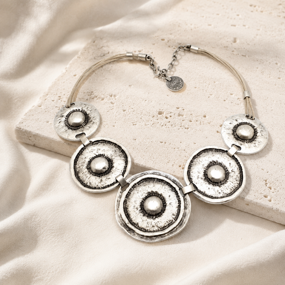 Hammered silver-tone circle necklace with a sculptural pendant design.