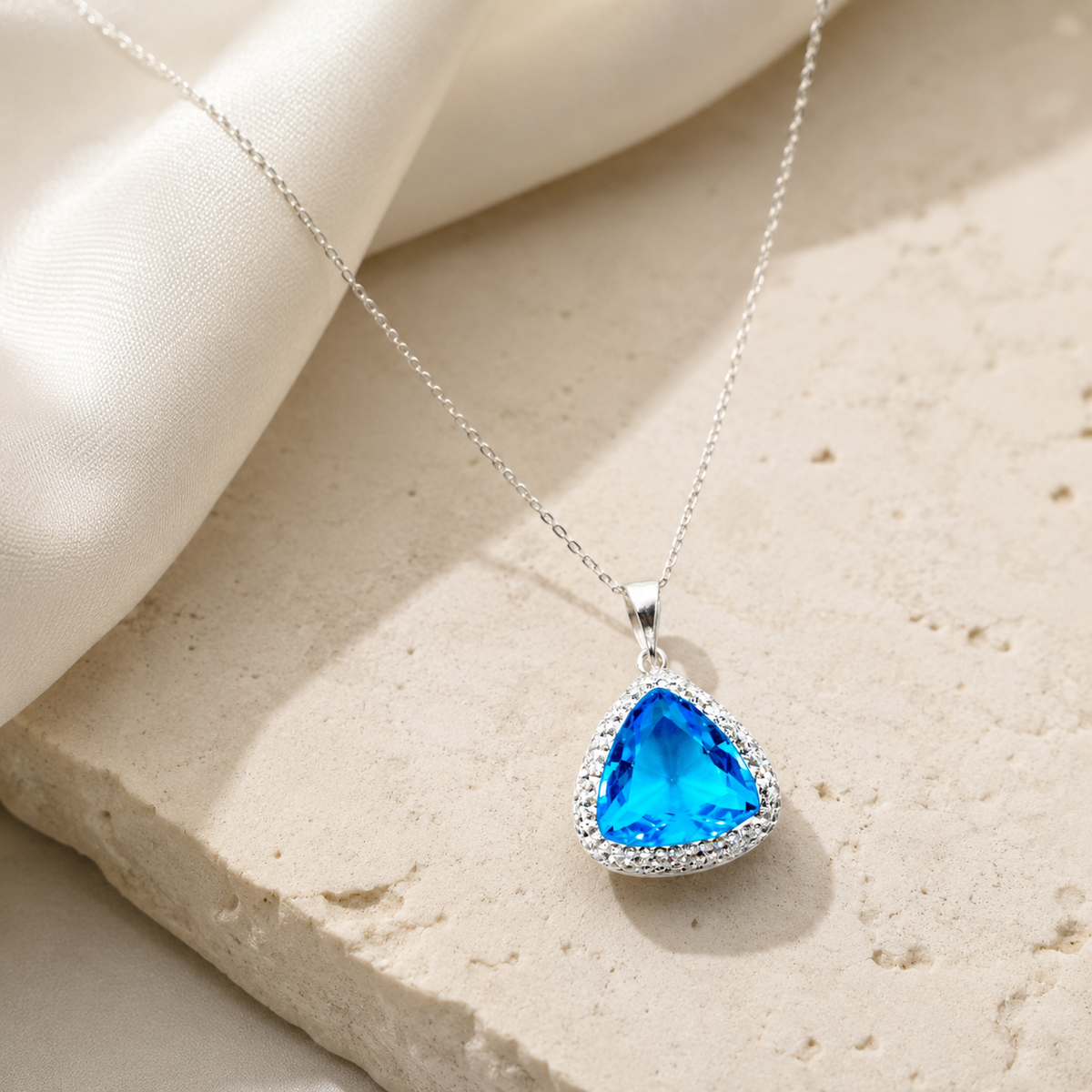 Triangle pendant necklace with a baby blue stone and silver-tone setting.