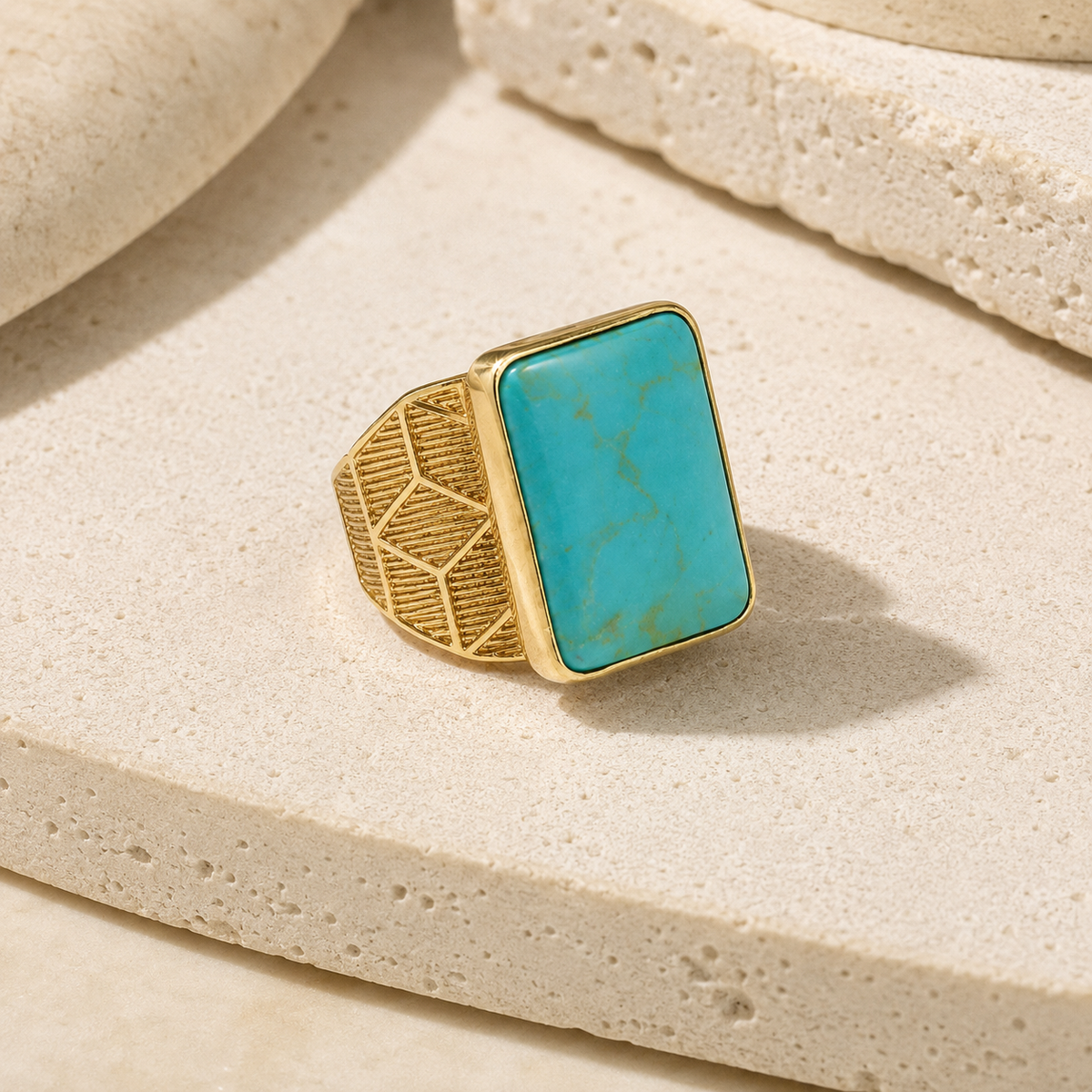 Angled view of a gold-plated ring with a square turquoise stone.
