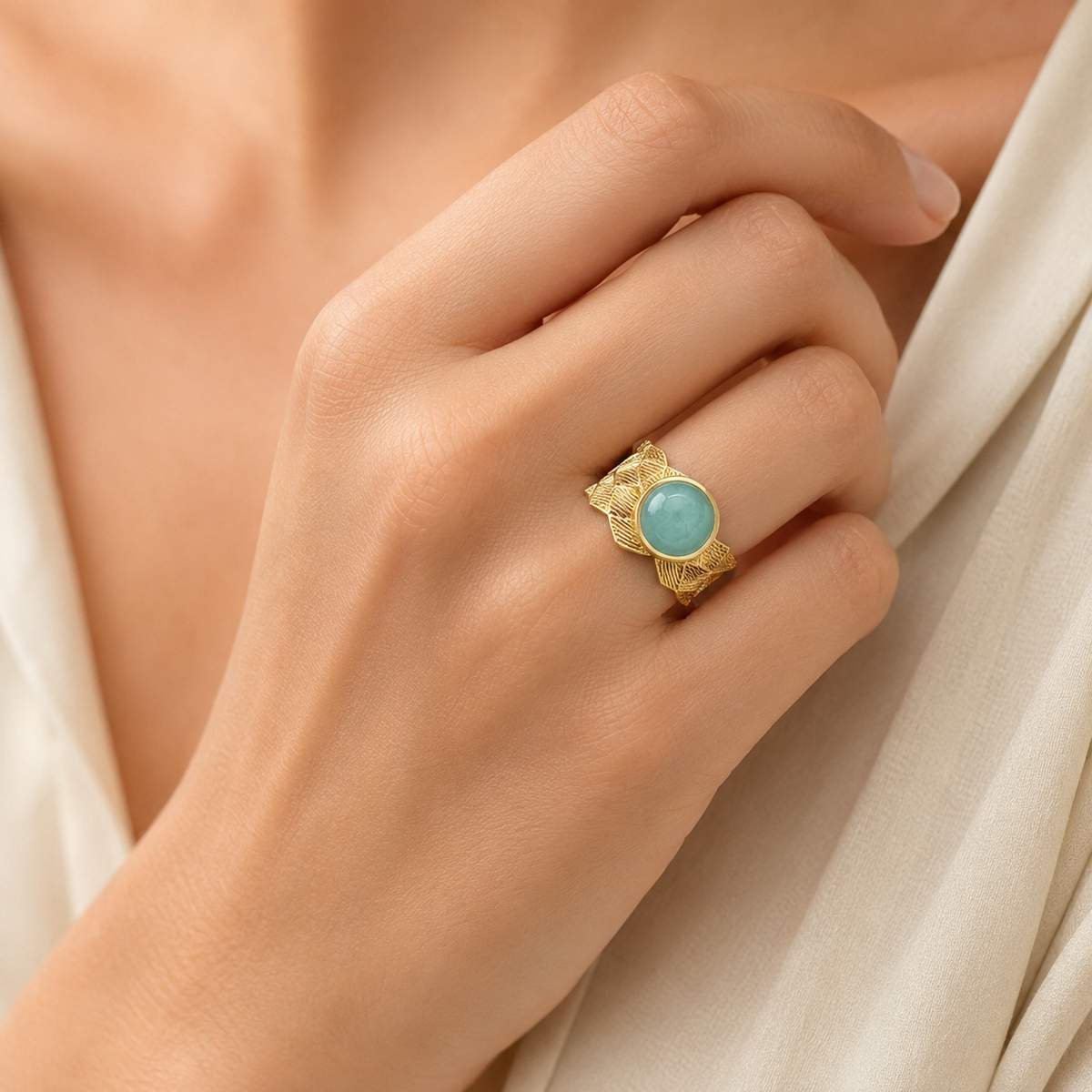 A gold-plated ring with a round aqua blue center shown from the front.