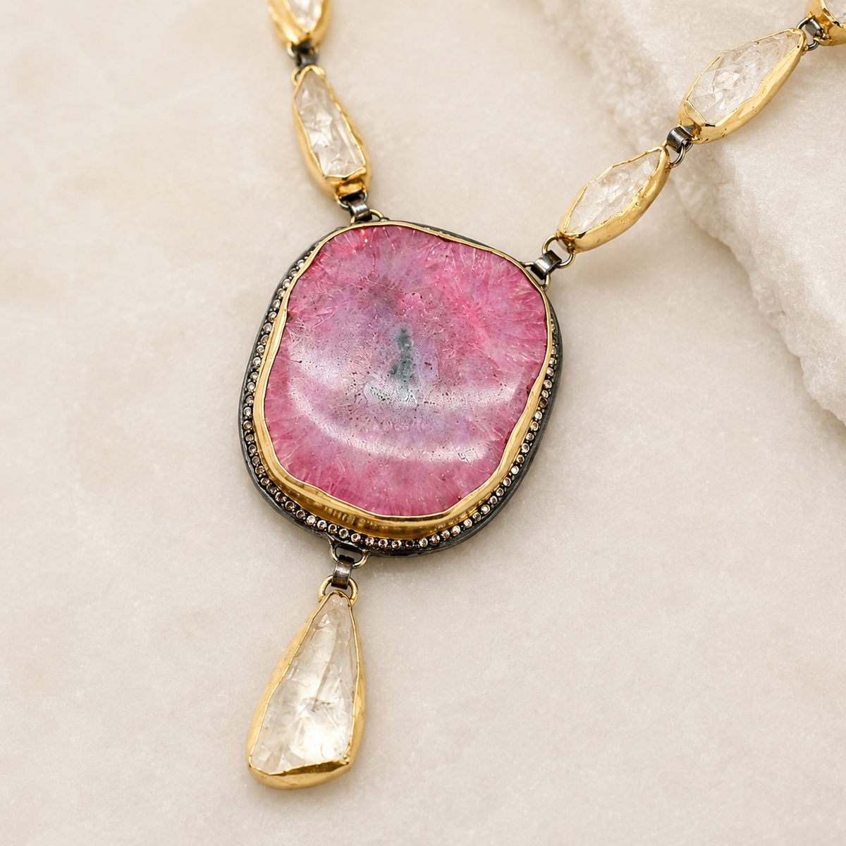 Close view of the pink solar stone pendant and teardrop accents.