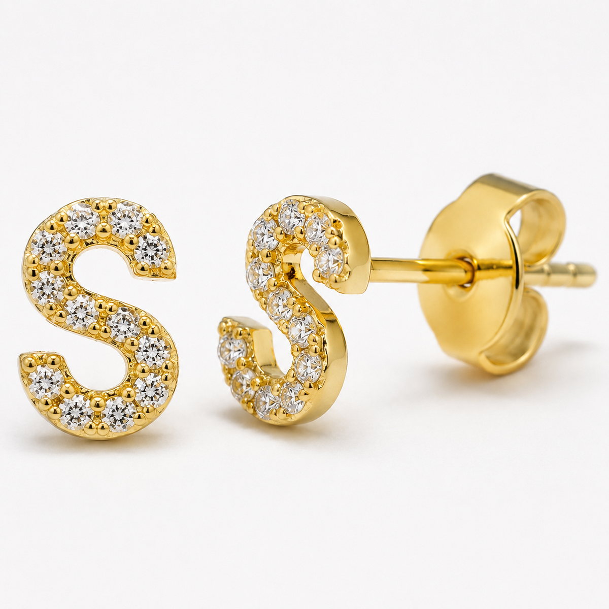 Close-up of a gold-tone initial stud earring with CZ details.
