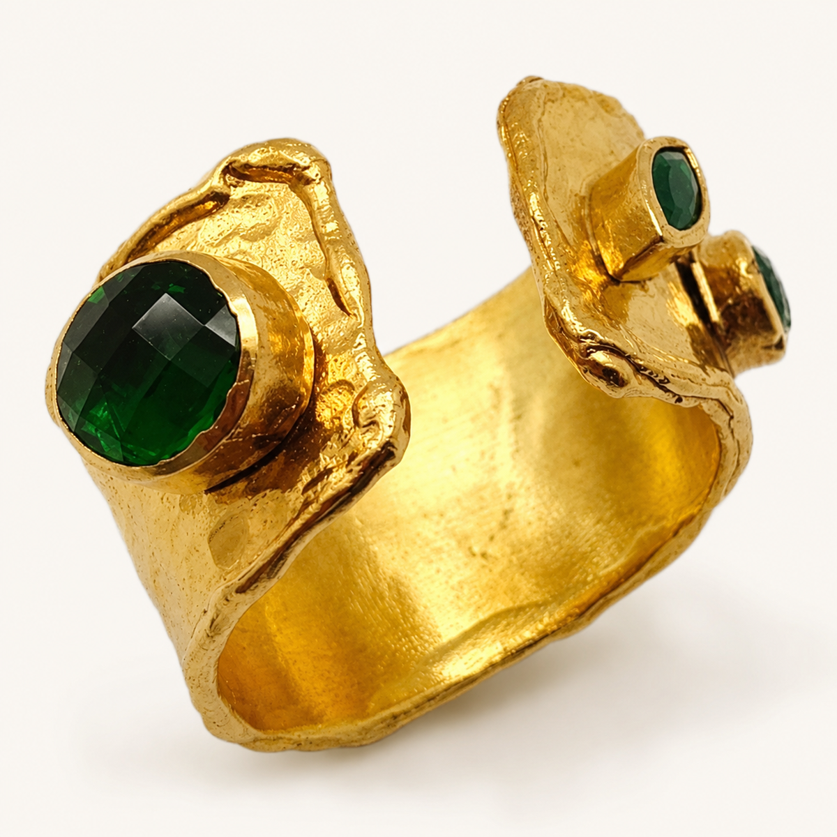 Close view of the emerald green stone and textured gold-plated setting on the ring.