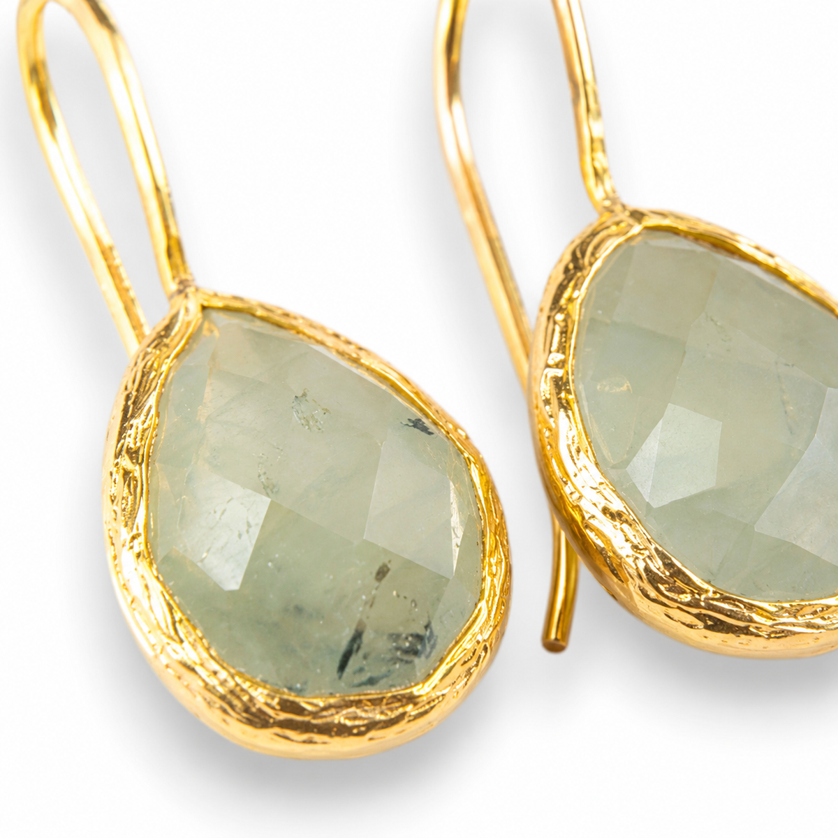Close view of teardrop earrings with polished gold-plated edges.
