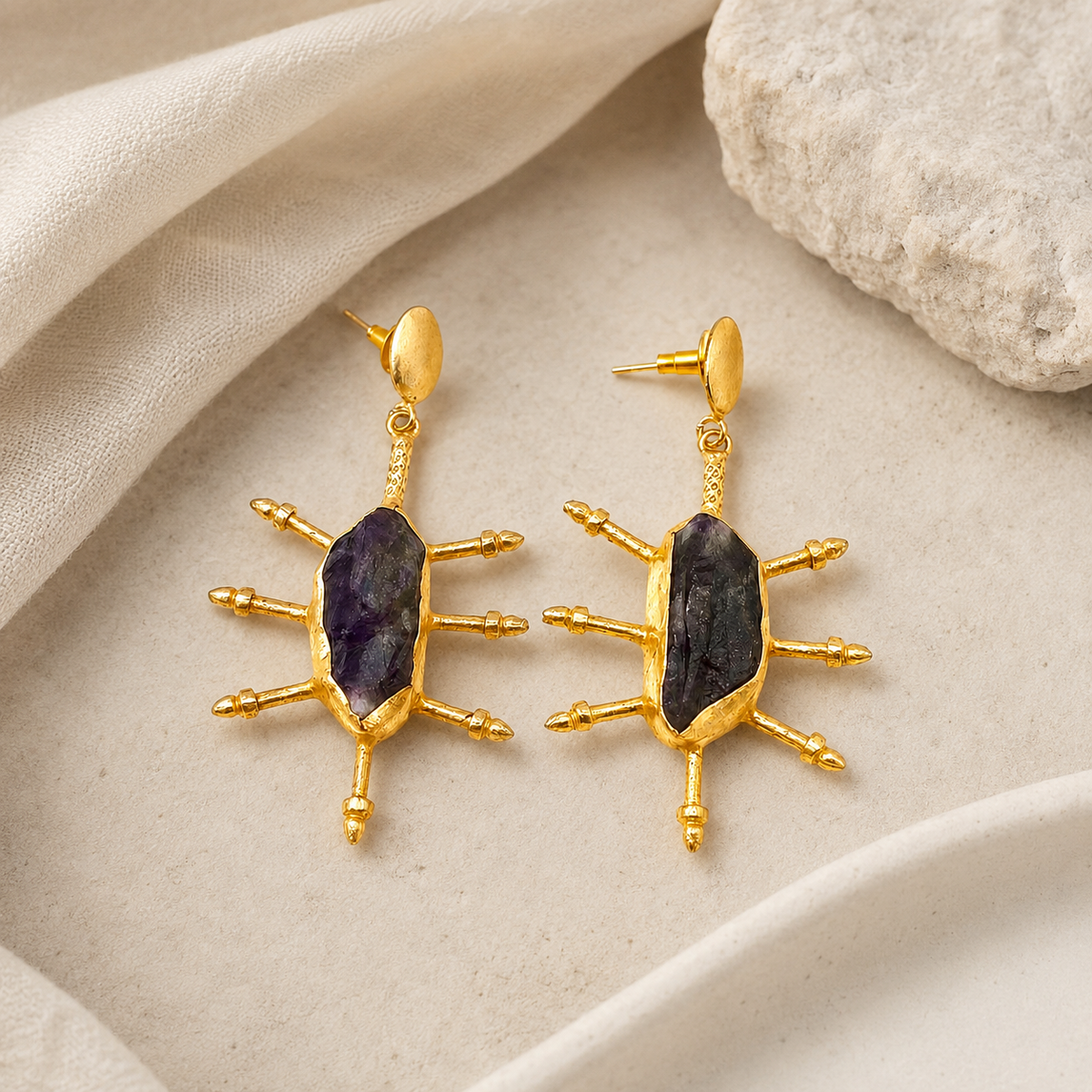 Gold-plated statement earrings with raw amethyst stones and sculptural spikes.