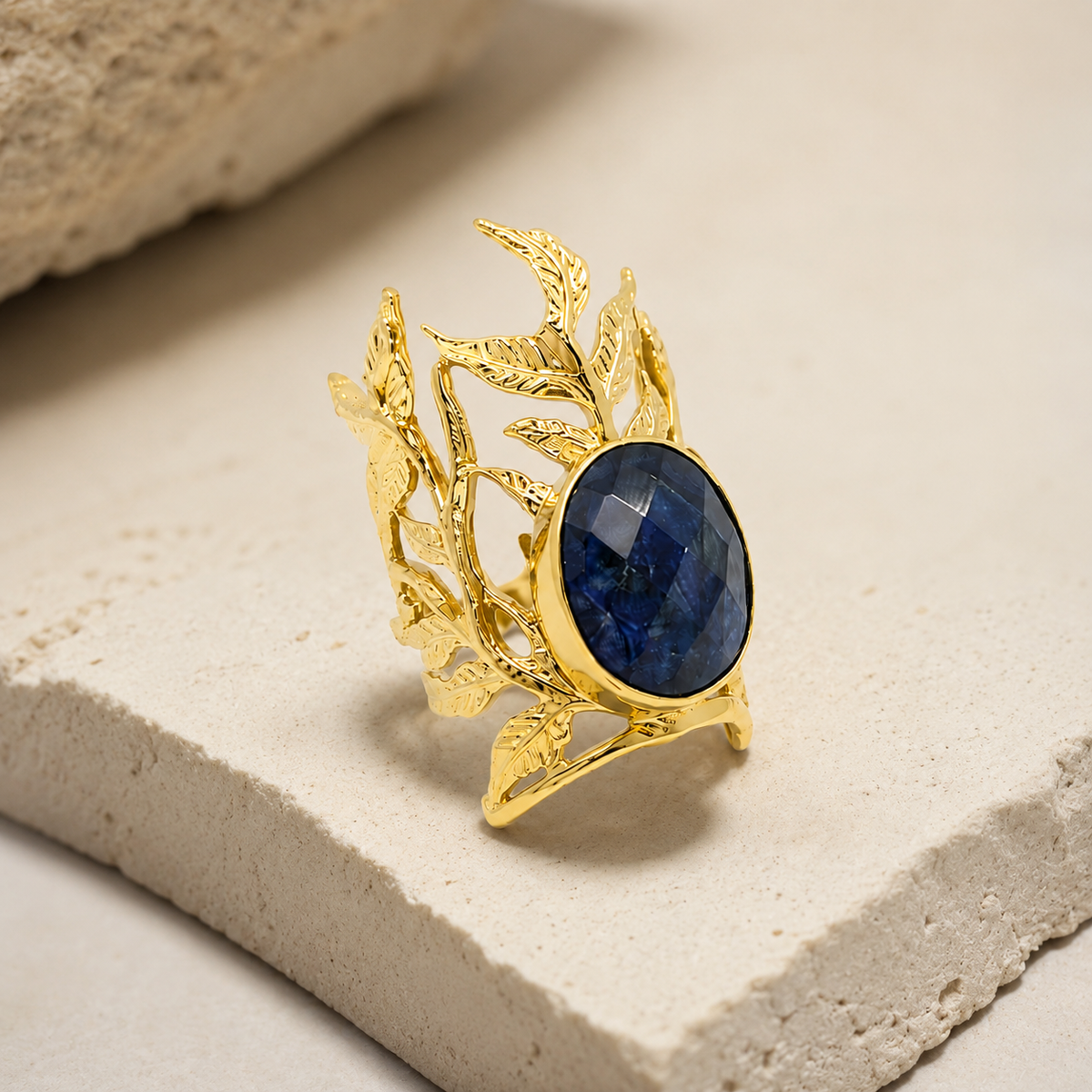 Gold statement ring with a navy blue oval center stone shown from the side.