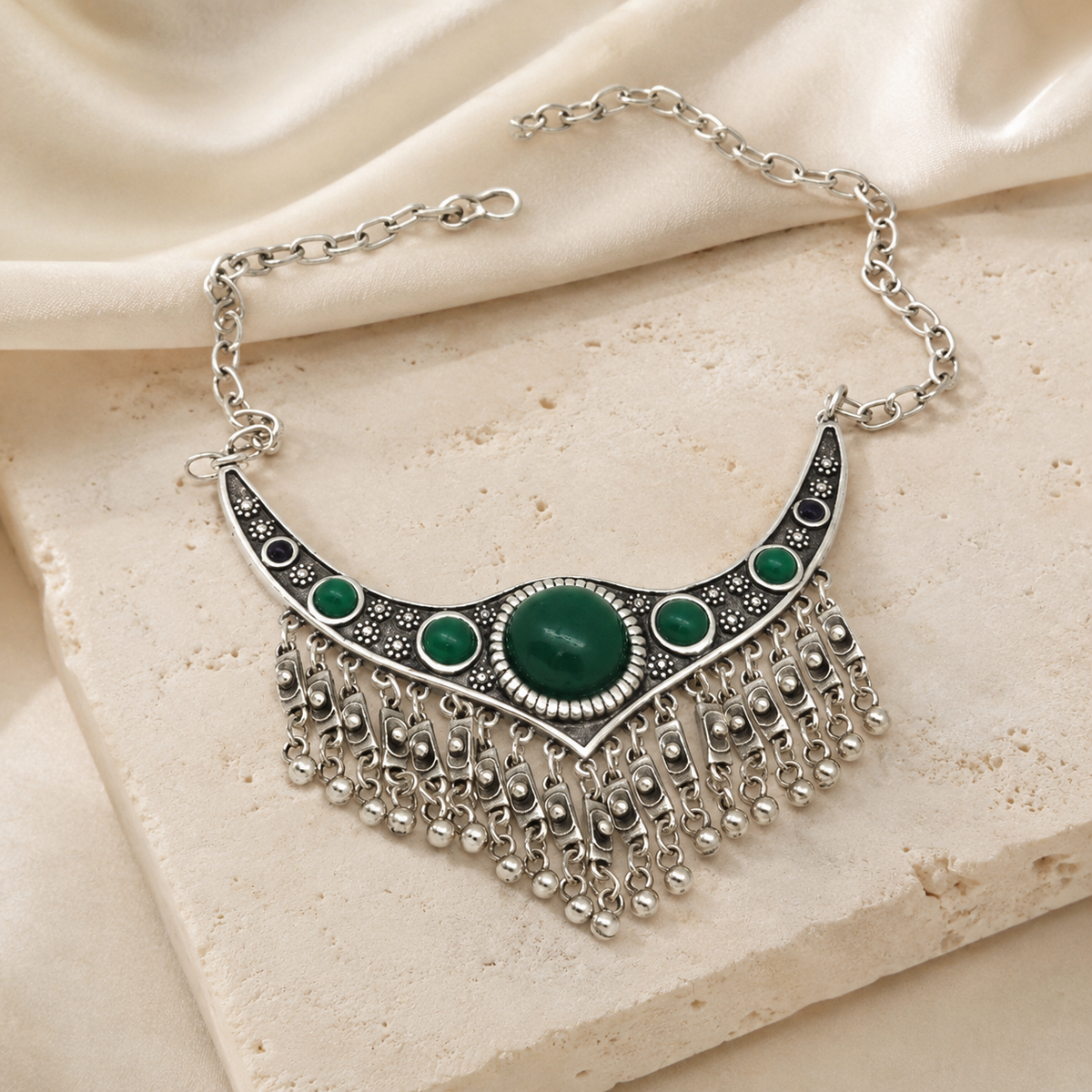 Collar necklace with green stone accents and dangling chain fringe.