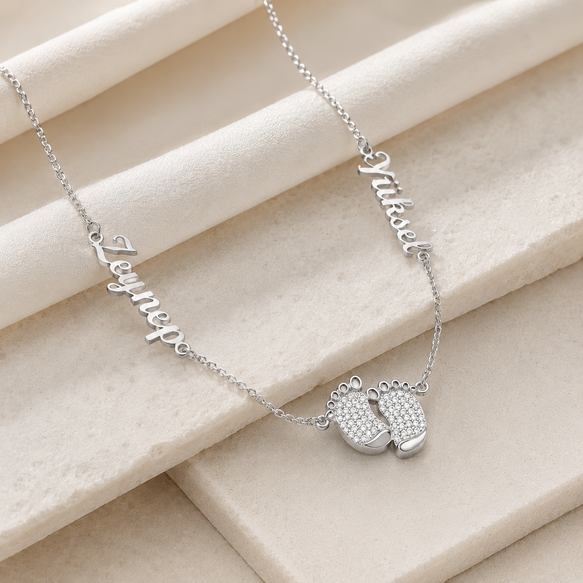 Angled view of a personalized baby feet necklace in a silver-tone finish.