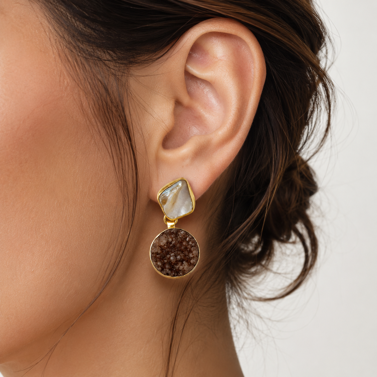 Pair of gold-plated earrings with black and neutral stone-like drops.
