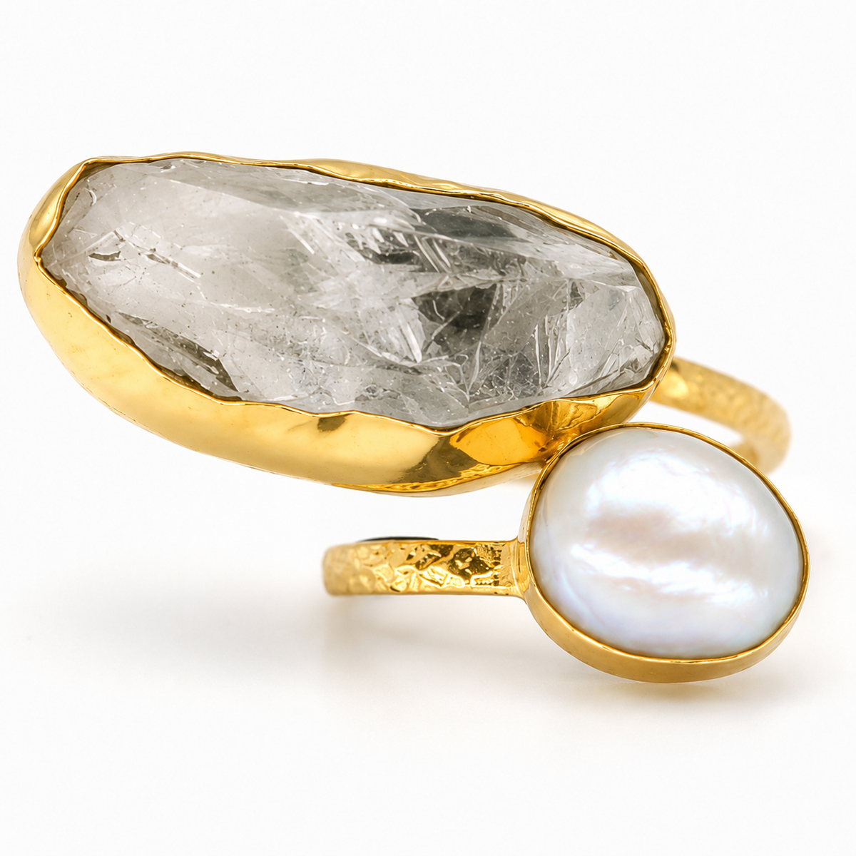 Close view of a gold-plated ring with a clear quartz stone and pearl-like accent.