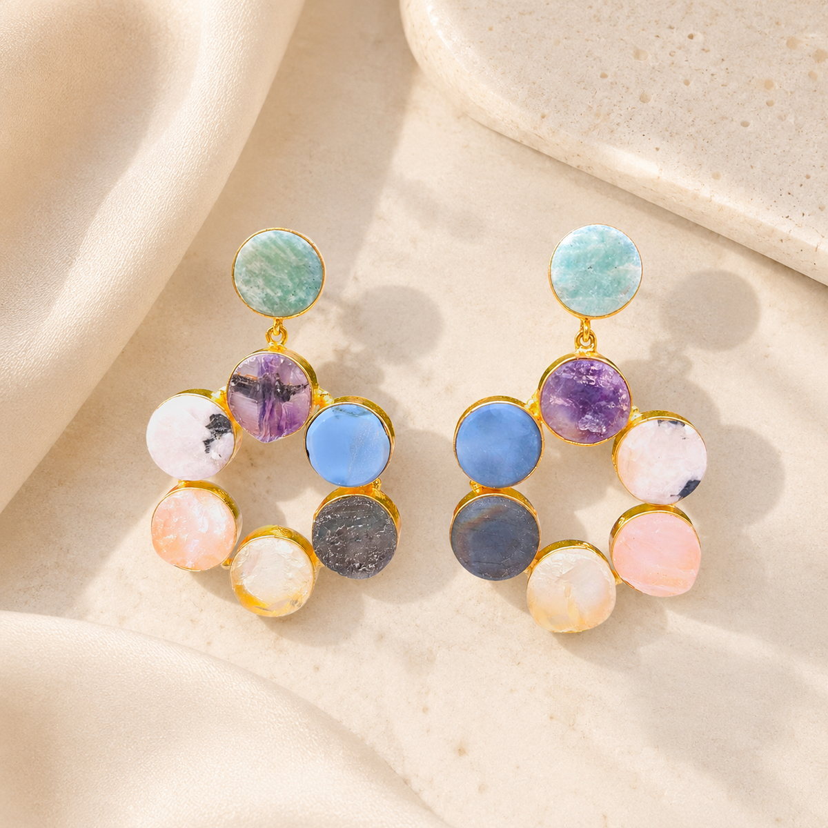 Gold-tone statement earrings with colorful round gemstone-style stones arranged in a hoop shape.